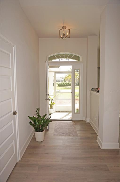 An entryway with light wood flooring, a potted plant, and a door leading to a porch — 26332 BARRANQUILLA AVENUE, PUNTA GORDA, FL