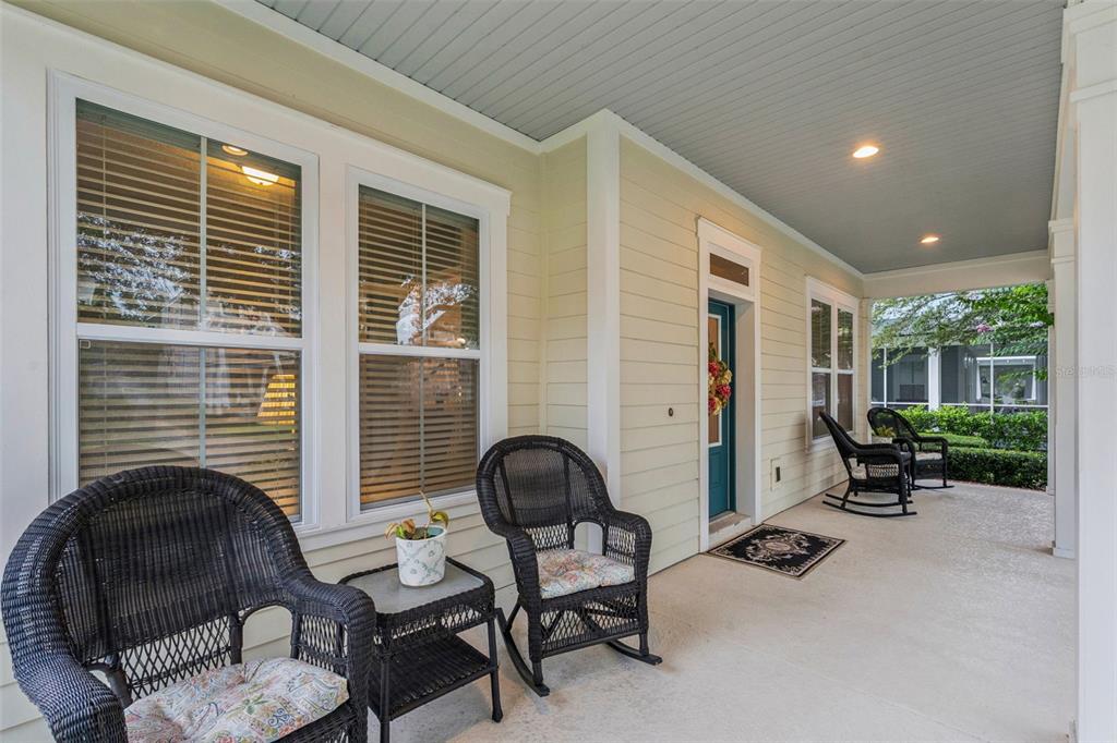 A covered front porch features light-colored siding, wicker rocking chairs, and a teal front door — 844 OAKLAND PARK BOULEVARD, WINTER GARDEN, FL
