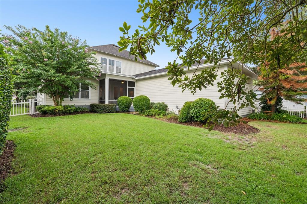 The backyard of a two-story house features a screened-in porch and manicured landscaping — 844 OAKLAND PARK BOULEVARD, WINTER GARDEN, FL