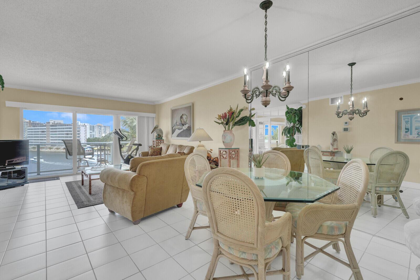 A living and dining room with tile floors, wicker chairs, and a balcony overlooking water — 140 NE 28th Avenue # 502, Pompano Beach FL 33062, POMPANO BEACH, FL