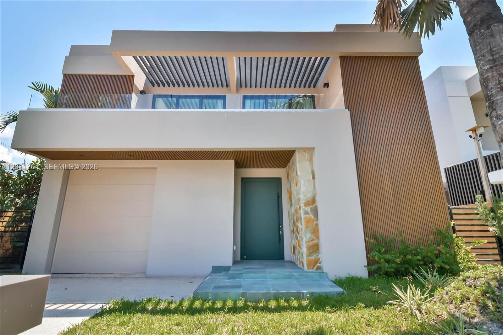 The exterior of a modern two-story house features wood-slat siding, a balcony, and stone accents — 135 SW 29th Rd, Miami FL 33129, MIAMI, FL