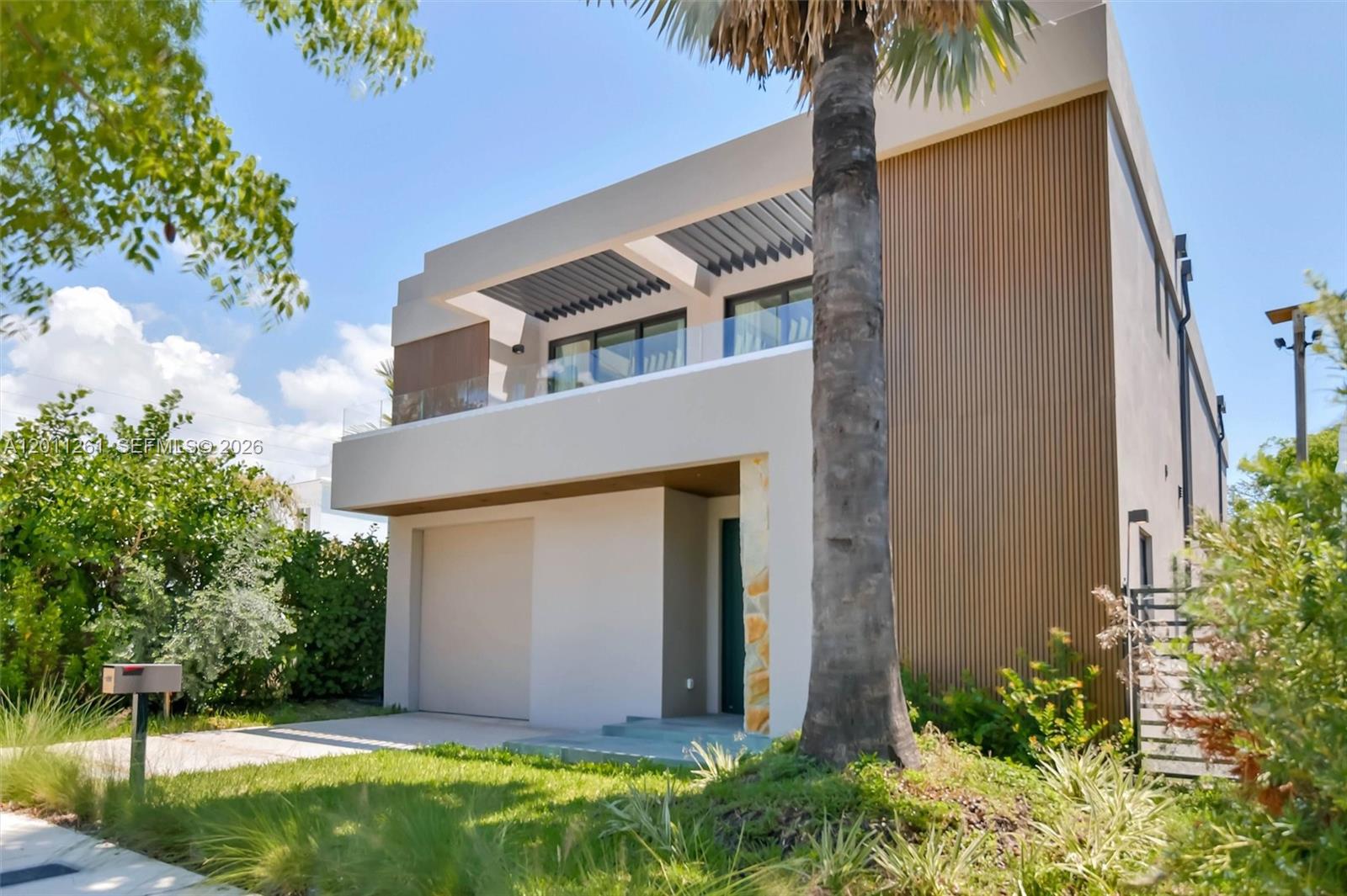 A modern two-story house features a garage, a second-floor balcony, and vertical wood-slat siding — 135 SW 29th Rd, Miami FL 33129, MIAMI, FL