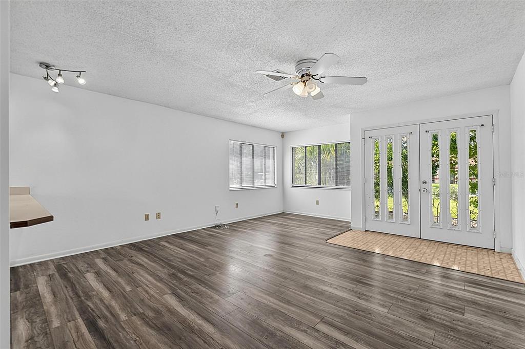 A living room with white walls, wood-look flooring, a ceiling fan, and double glass doors — 19 BLACKBERRY PLACE, PALM COAST, FL