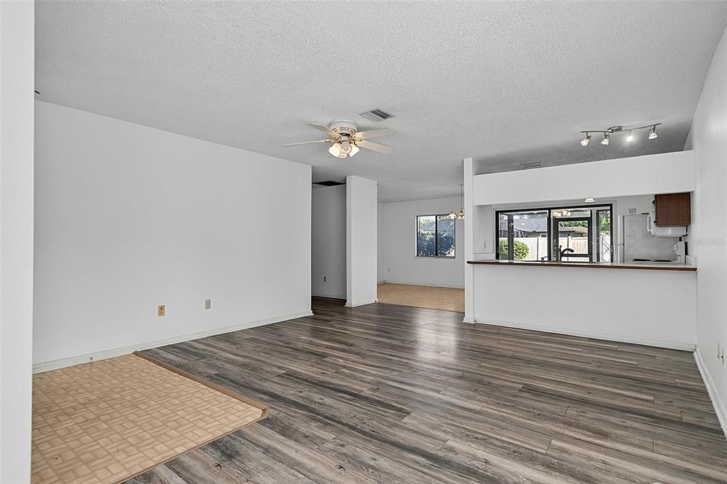 A living room with wood-look flooring, a ceiling fan, and an open kitchen pass-through — 19 BLACKBERRY PLACE, PALM COAST, FL