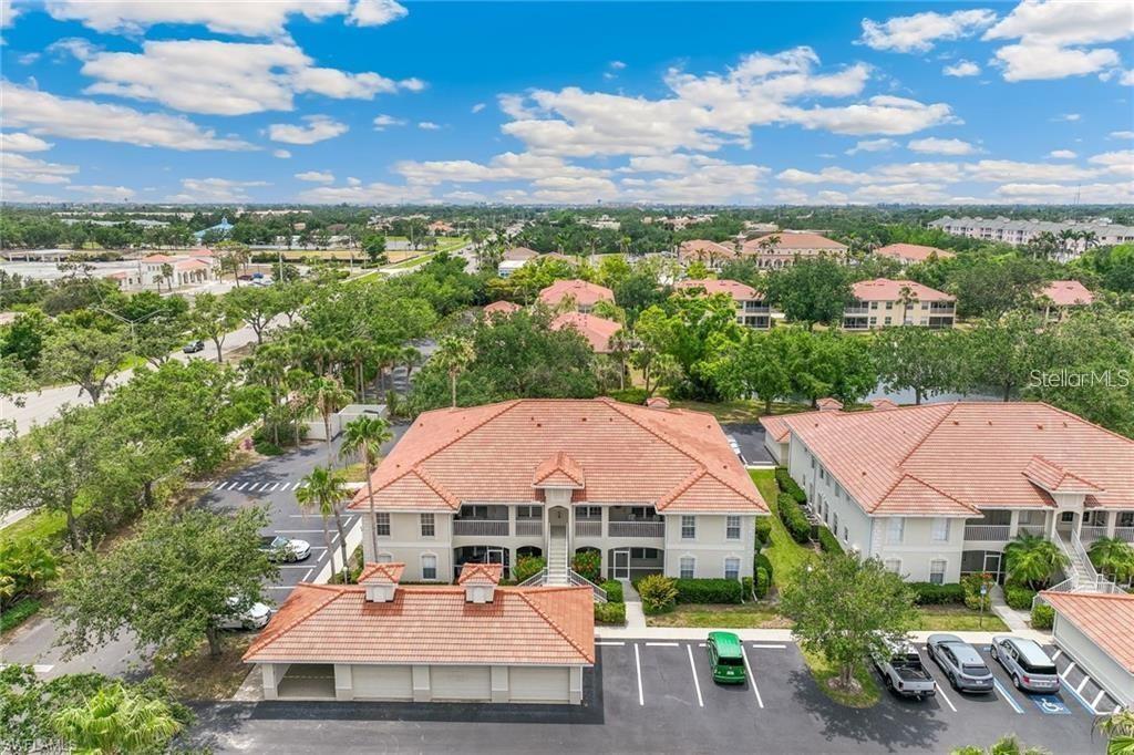 An aerial view shows a multi-story apartment building with a tile roof and parking lot — 10202 L PAVIA BOULEVARD UNIT 10202, VENICE, FL