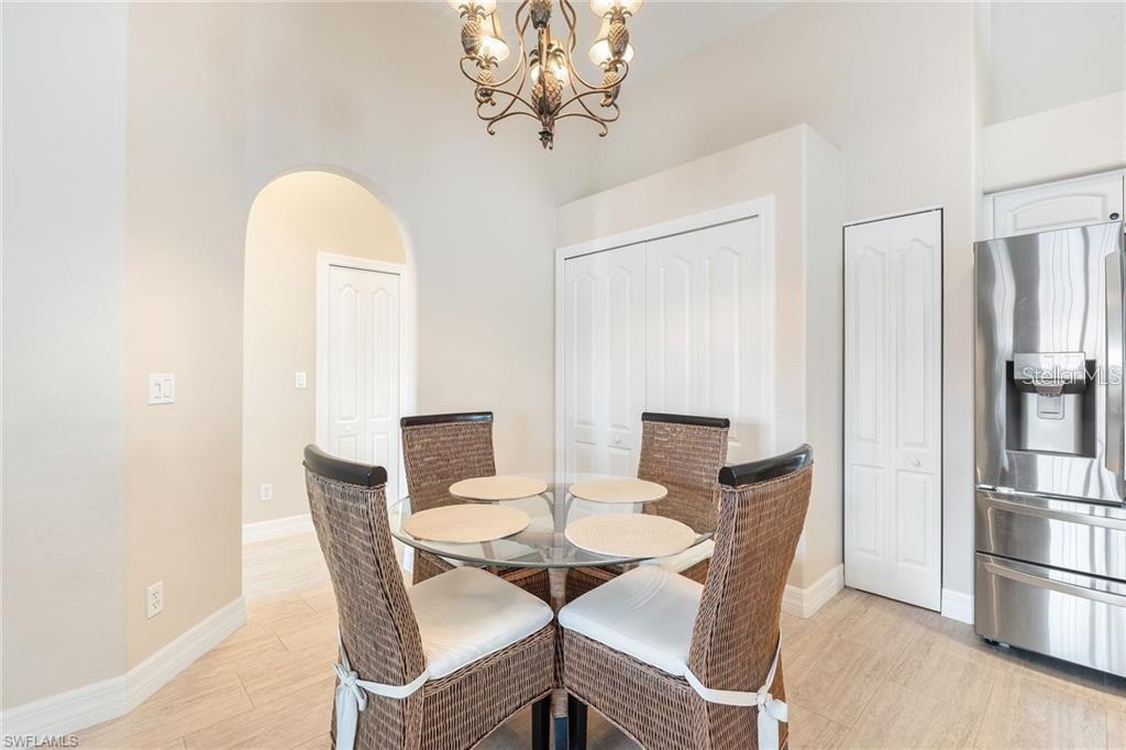 A dining area features a glass-topped table, four wicker chairs, and a pineapple-themed chandelier — 10202 L PAVIA BOULEVARD UNIT 10202, VENICE, FL