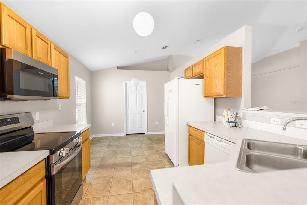 A kitchen with oak cabinets, stainless steel appliances, and tile flooring — 3220 BELLERICAY LANE, LAND O LAKES, FL