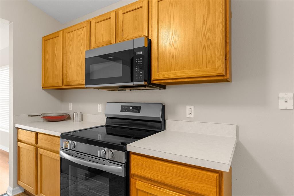 A kitchen features oak cabinets, stainless steel appliances, and light-colored laminate countertops — 3220 BELLERICAY LANE, LAND O LAKES, FL