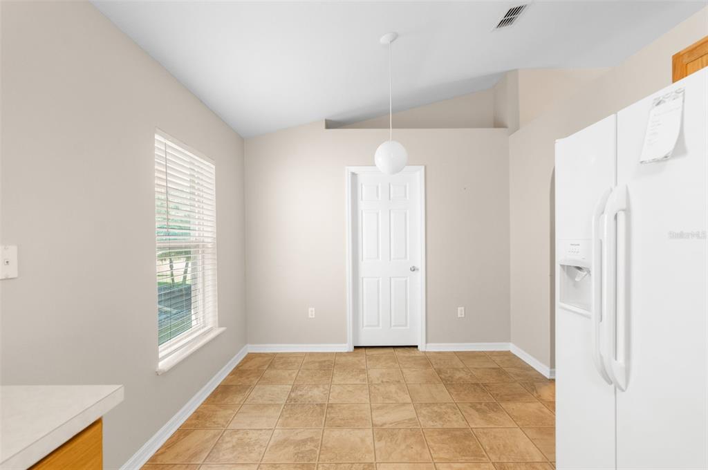 A kitchen dining area with tile flooring, a white door, and a pendant light — 3220 BELLERICAY LANE, LAND O LAKES, FL
