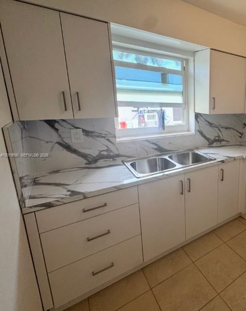 A kitchen features white cabinets, a marble-patterned backsplash, and a stainless steel double sink — 2212 Liberty St # 1, Hollywood FL 33020, HOLLYWOOD, FL