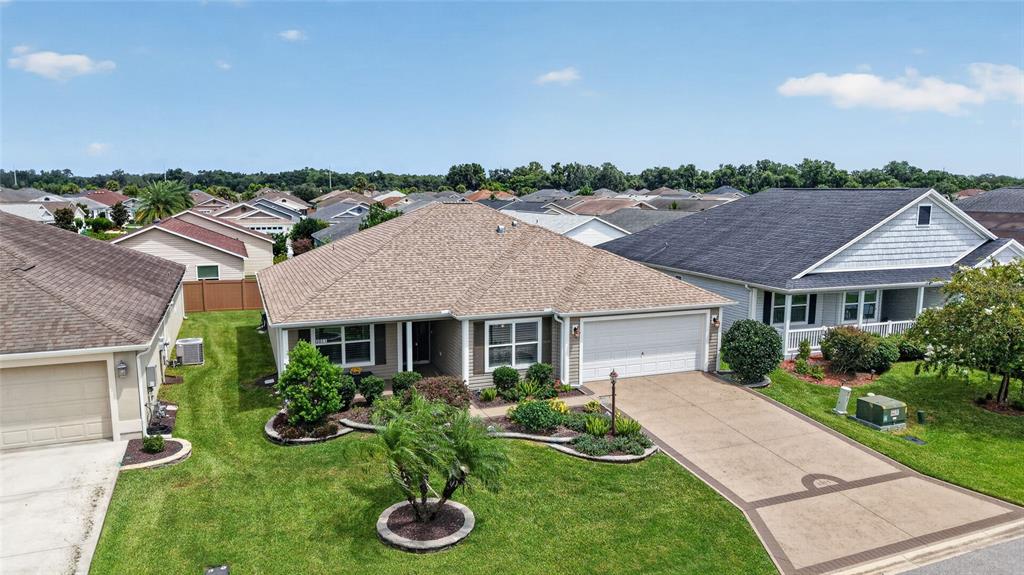 An aerial view of a suburban single-story house with a tan roof and driveway — 3011 SPANISH MOSS WAY, THE VILLAGES, FL