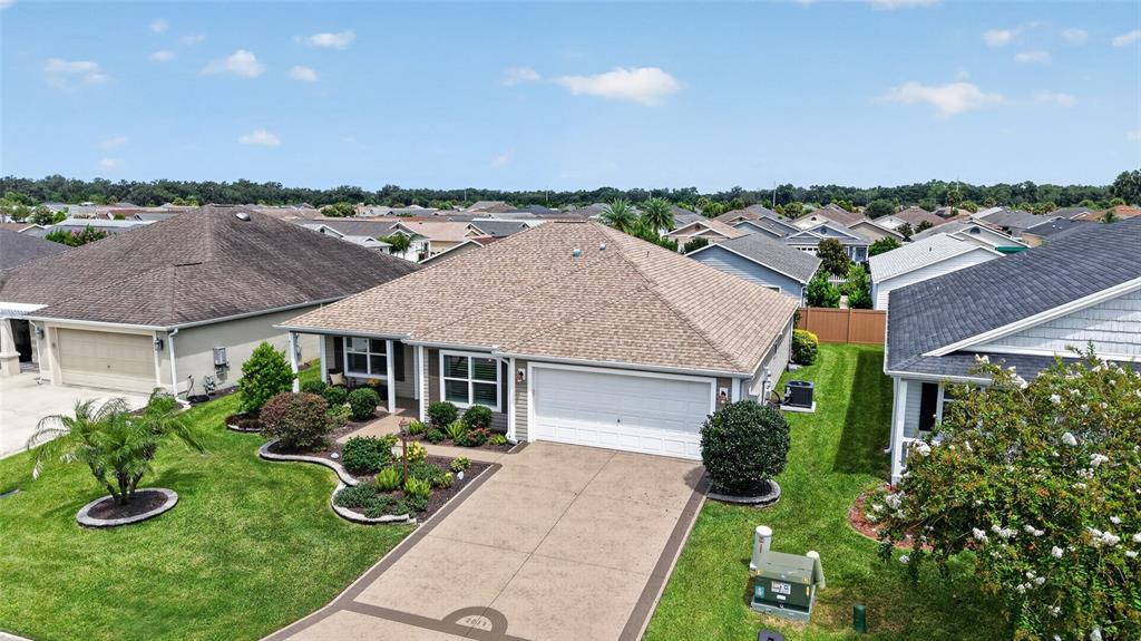 An aerial view shows a single-story house with a tan roof and a concrete driveway — 3011 SPANISH MOSS WAY, THE VILLAGES, FL