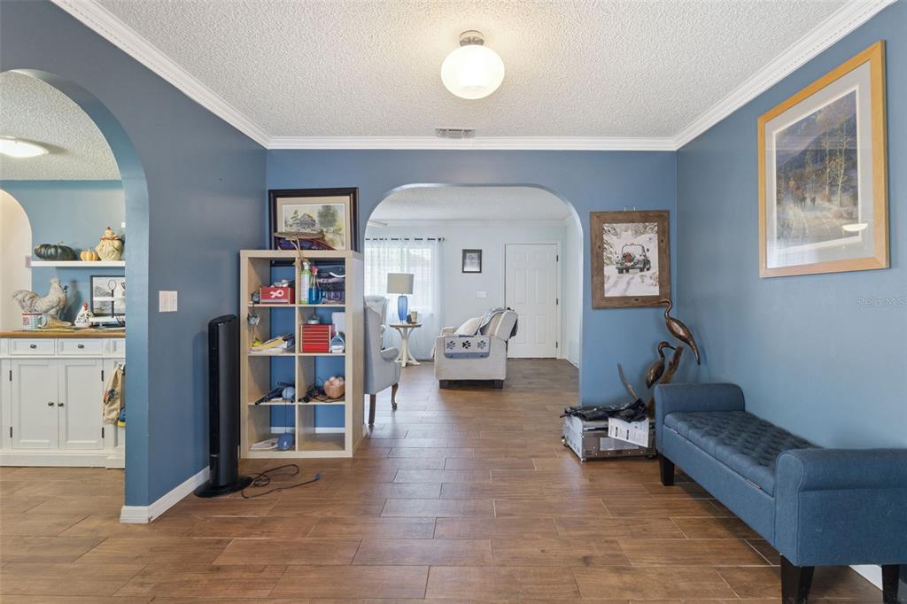 A living area with blue walls, tiled floors, and arched doorways leading to other rooms — 17841 SE 106TH COURT, SUMMERFIELD, FL