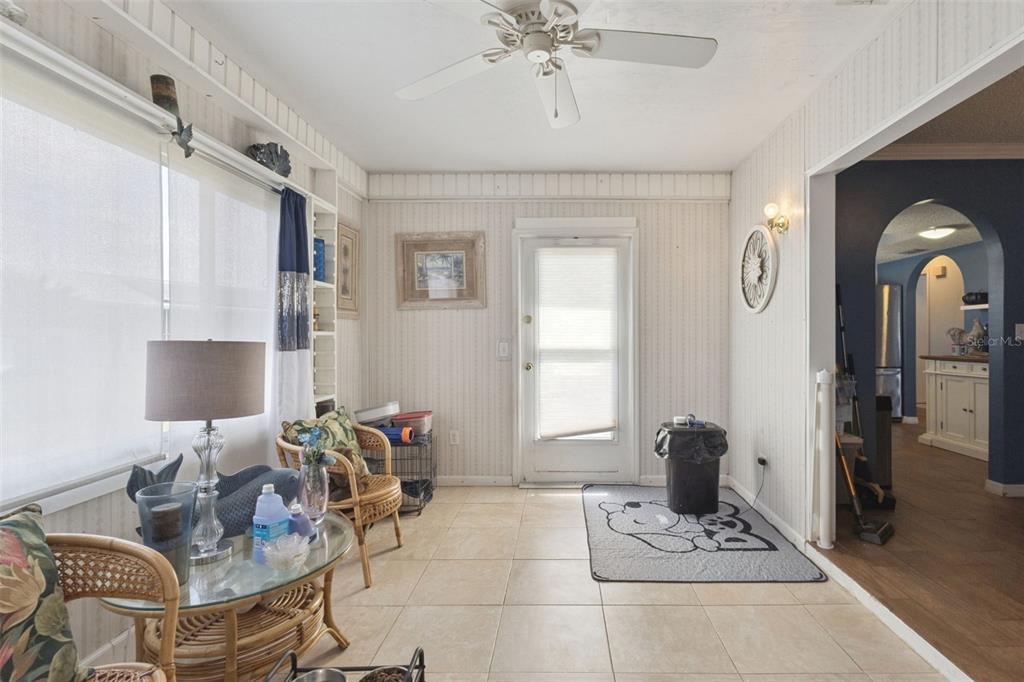 A sunroom features tiled floors, vertical wood paneling, a ceiling fan, and a glass door — 17841 SE 106TH COURT, SUMMERFIELD, FL