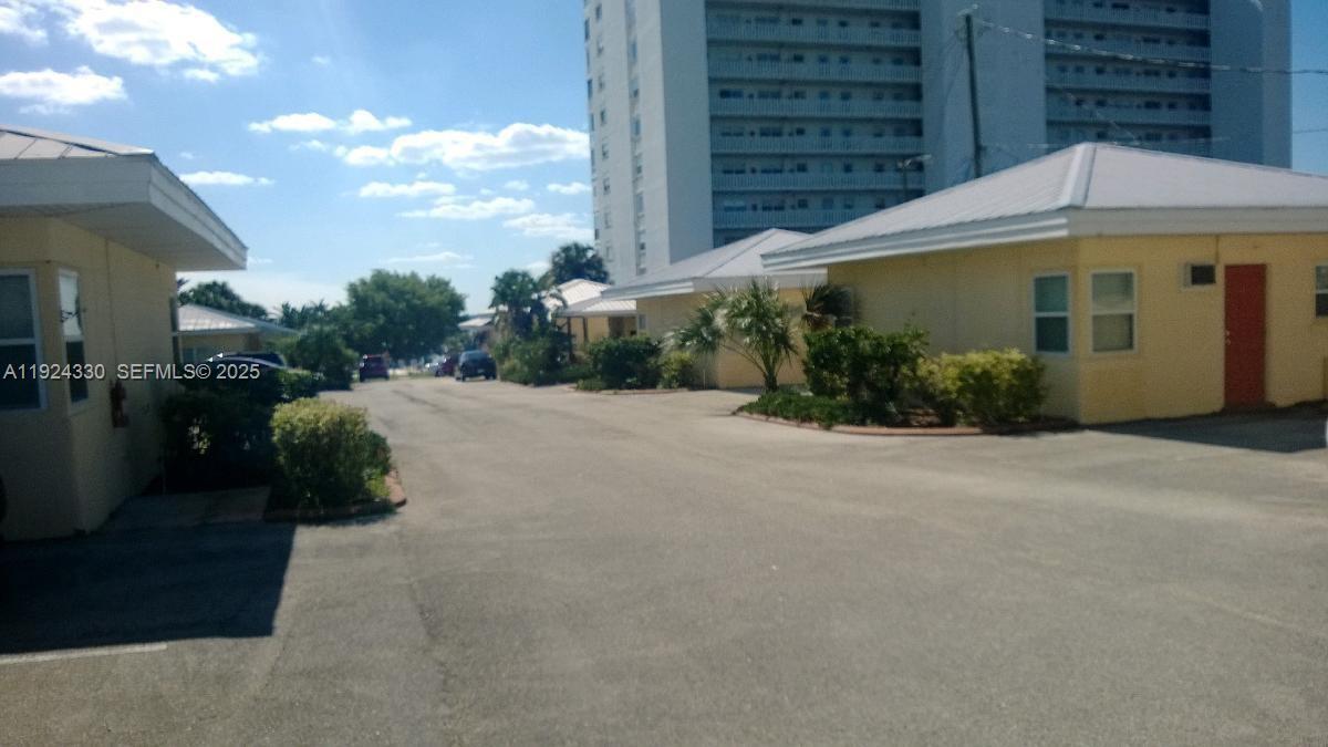 A paved driveway leads between two yellow one-story buildings toward a tall residential tower — 2121 LAKEVIEW DRIVE, Sebring FL 33870, SEBRING, FL