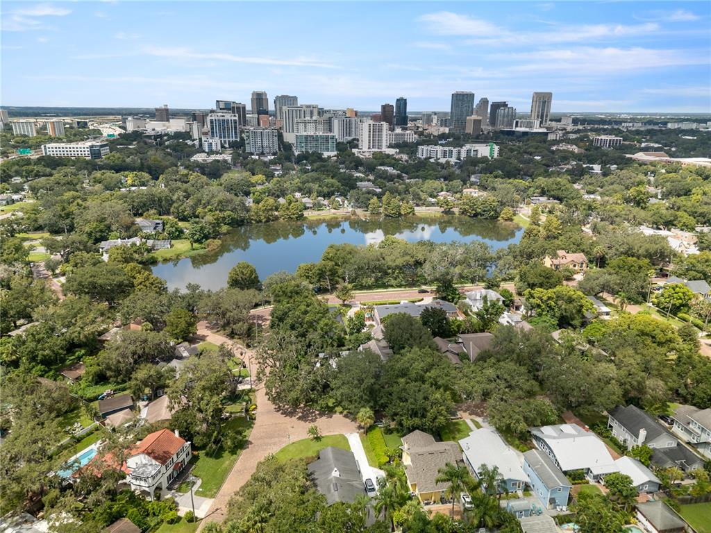 An aerial view shows a lake surrounded by trees and houses with a city skyline — 1408 E CHURCH STREET, ORLANDO, FL