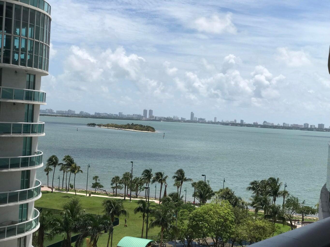 A view from a high-rise balcony overlooking a park, a bay, and a distant city skyline — 488 NE 18th Street # 807, Miami FL 33132, MIAMI, FL