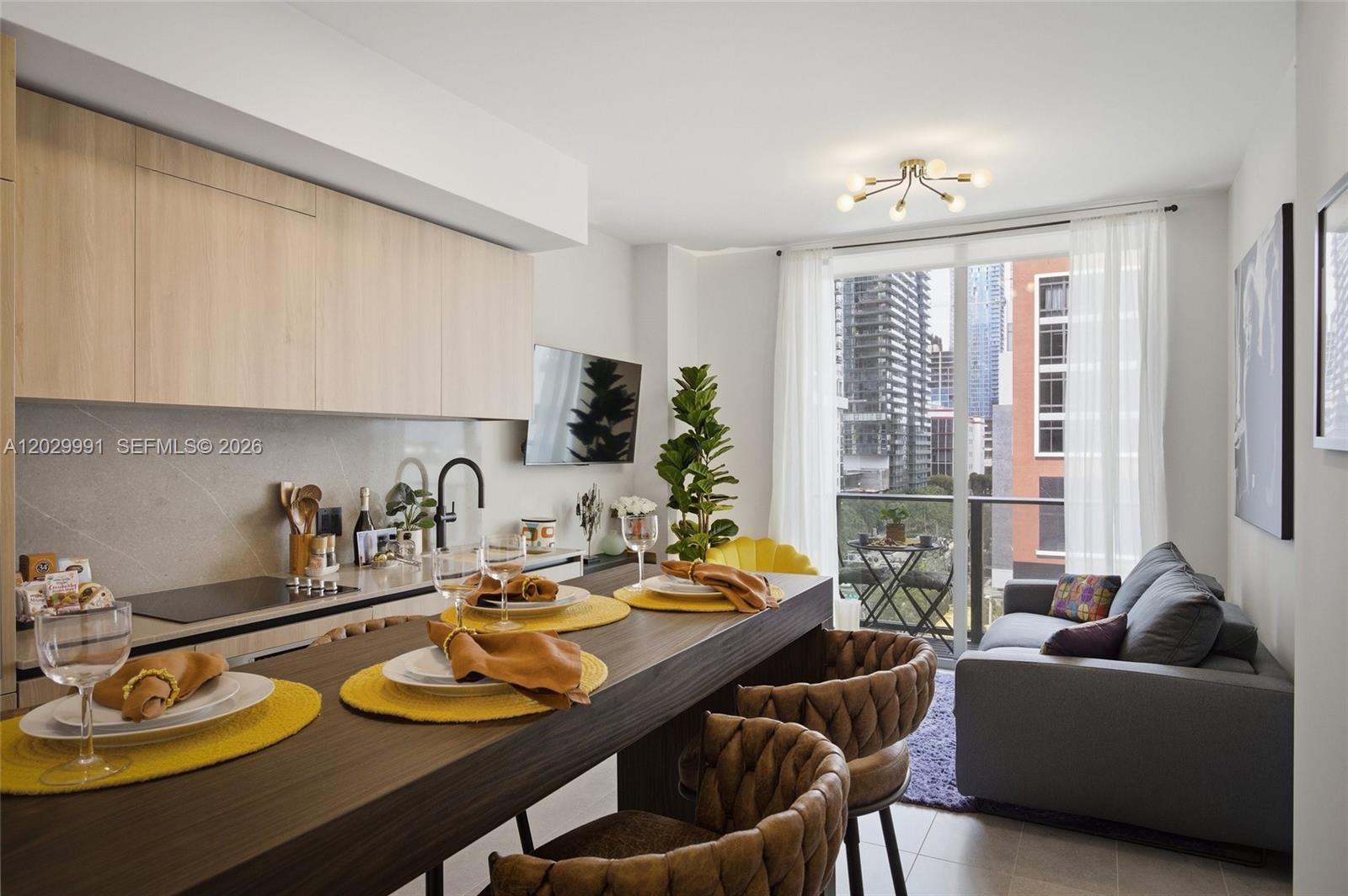 A modern kitchen and dining area features a long wooden table, chairs, and balcony access — 121 NE 5th St # 711, Miami FL 33132, MIAMI, FL