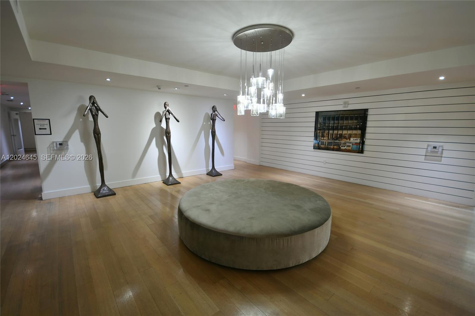 A modern lobby features hardwood floors, a circular ottoman, three bronze sculptures, and a chandelier — 201 SW 17th Rd # 304, Miami FL 33129, MIAMI, FL