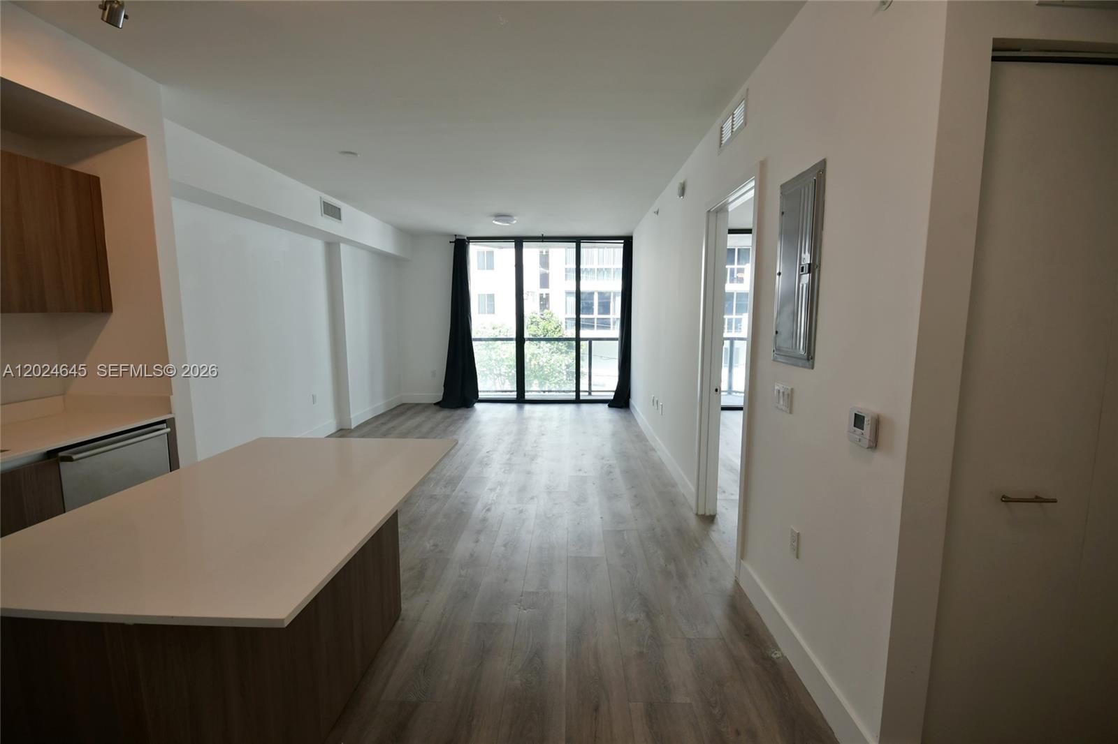 An open-concept living area features wood-look flooring, a kitchen island, and floor-to-ceiling windows — 201 SW 17th Rd # 304, Miami FL 33129, MIAMI, FL