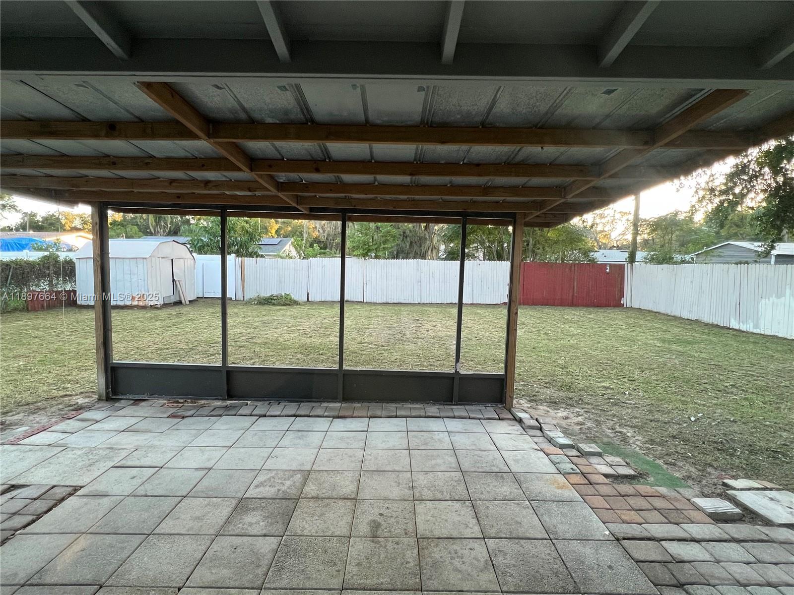 A covered patio with a screened enclosure overlooks a fenced backyard with a storage shed — 6632 Edgewater Drive # 0, Orlando FL 32810, ORLANDO, FL
