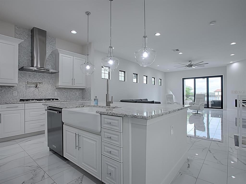 A modern white kitchen features a large island with a farmhouse sink and pendant lights — 7661 TOSCANA BOULEVARD, ORLANDO, FL