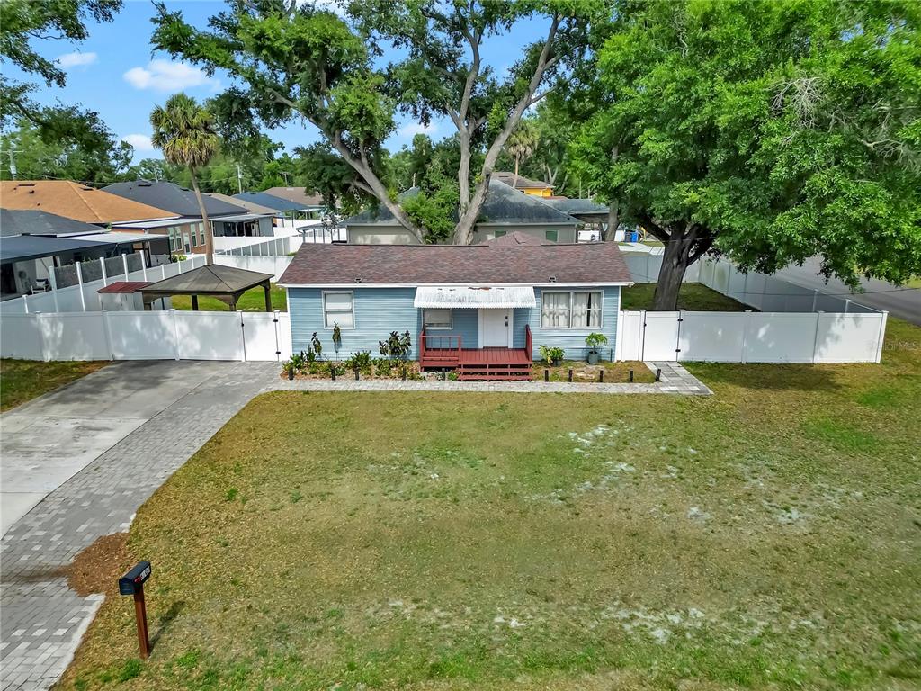 A blue single-story house with a red porch and white fence sits on a lawn — 6201 THERESA STREET, TAMPA, FL