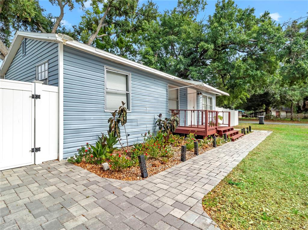 A light blue house with a paver walkway, a small wooden deck, and landscaping — 6201 THERESA STREET, TAMPA, FL