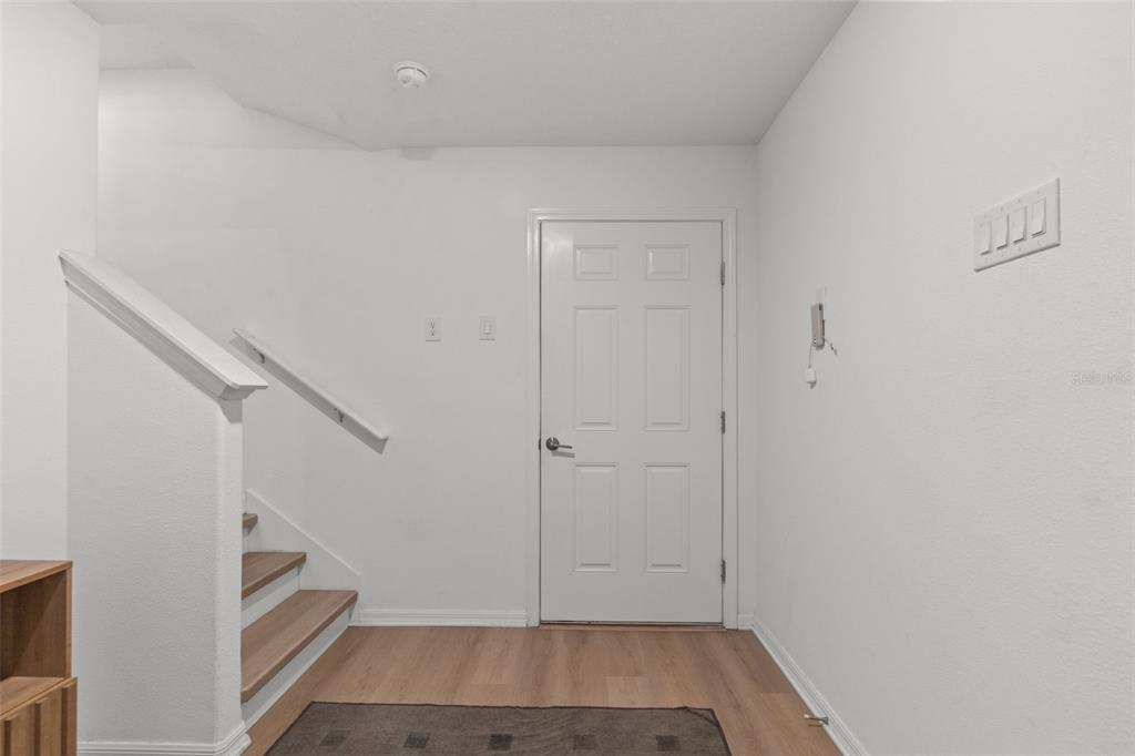 An entryway features a white door, light wood flooring, and a staircase with a handrail — 4720 TUSCAN LOON DRIVE, TAMPA, FL