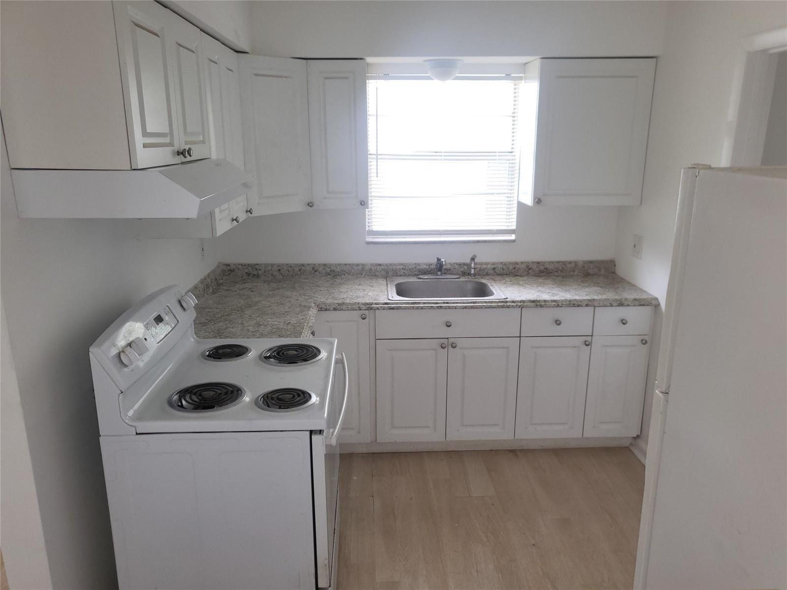 A kitchen features white cabinets, a white electric stove, a sink, and light-colored countertops — 2185 NW 3rd Street, Okeechobee FL 34972, OKEECHOBEE, FL