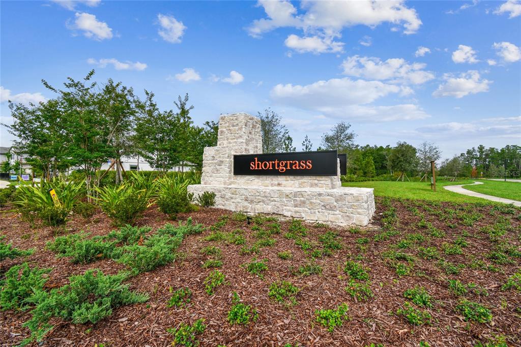 A stone monument sign for a community named Shortgrass stands in a landscaped area — 1724 RIVULET WAY, ZEPHYRHILLS, FL