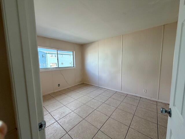 An empty bedroom features beige paneled walls, light-colored tile flooring, and a single window — 1829 N A Street # 66, FL 33460, FL