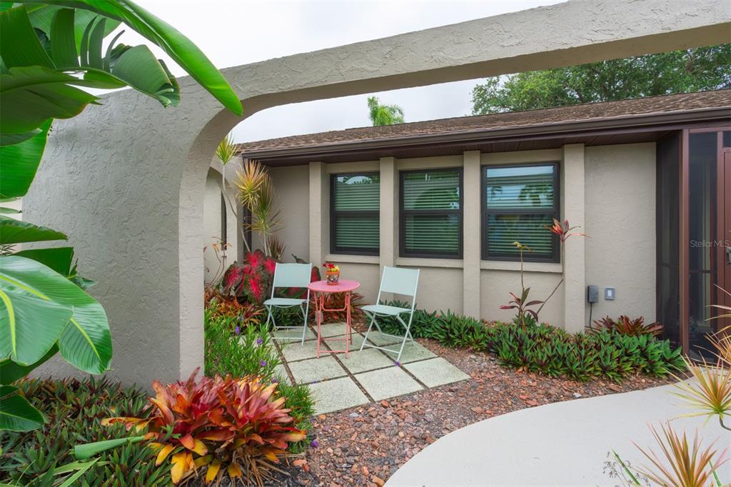 A small patio with two chairs and a table sits outside a house with windows — 2360 BAL HARBOUR DRIVE, VENICE, FL