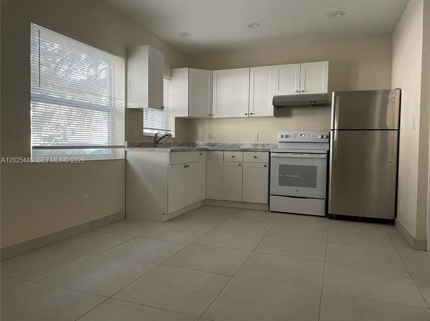 A kitchen features white cabinets, stainless steel appliances, and light-colored tile flooring — 1720 Pierce St # 3, Hollywood FL 33020, HOLLYWOOD, FL