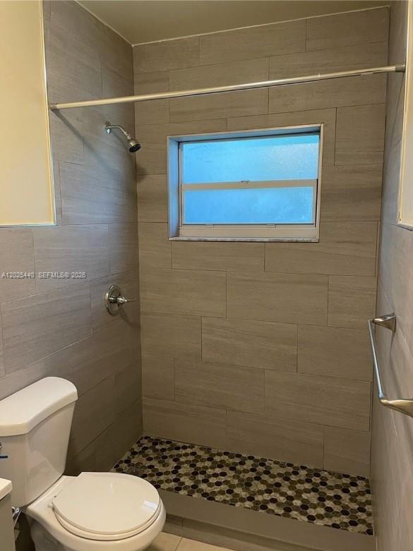 A bathroom features a shower with gray tile walls, a window, and a mosaic floor — 1720 Pierce St # 3, Hollywood FL 33020, HOLLYWOOD, FL