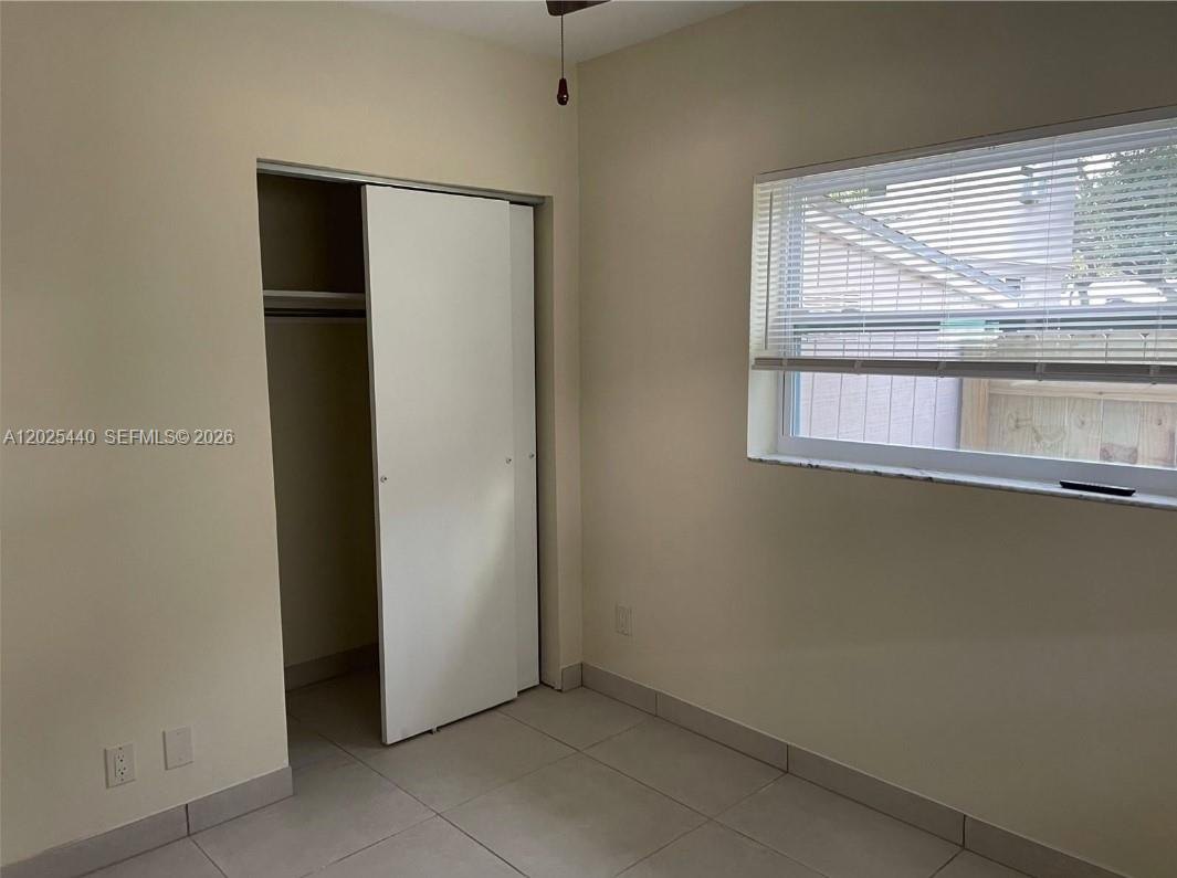 A bedroom features light-colored tile flooring, a sliding closet door, and a window with blinds — 1720 Pierce St # 3, Hollywood FL 33020, HOLLYWOOD, FL