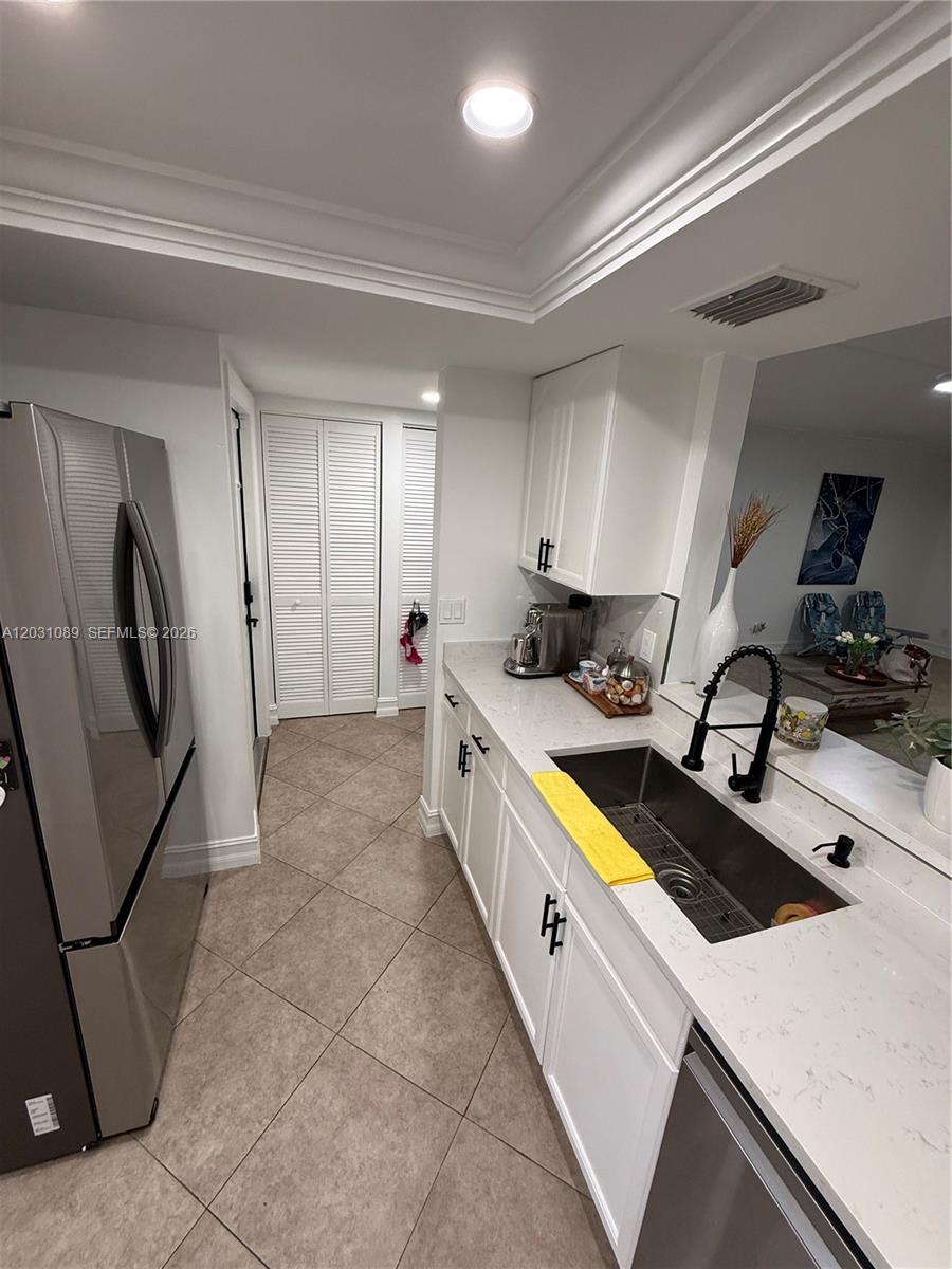 A kitchen features white cabinets, quartz countertops, a stainless steel sink, and tile flooring — 1020 NW 80th Ave # 104, Margate FL 33063, MARGATE, FL