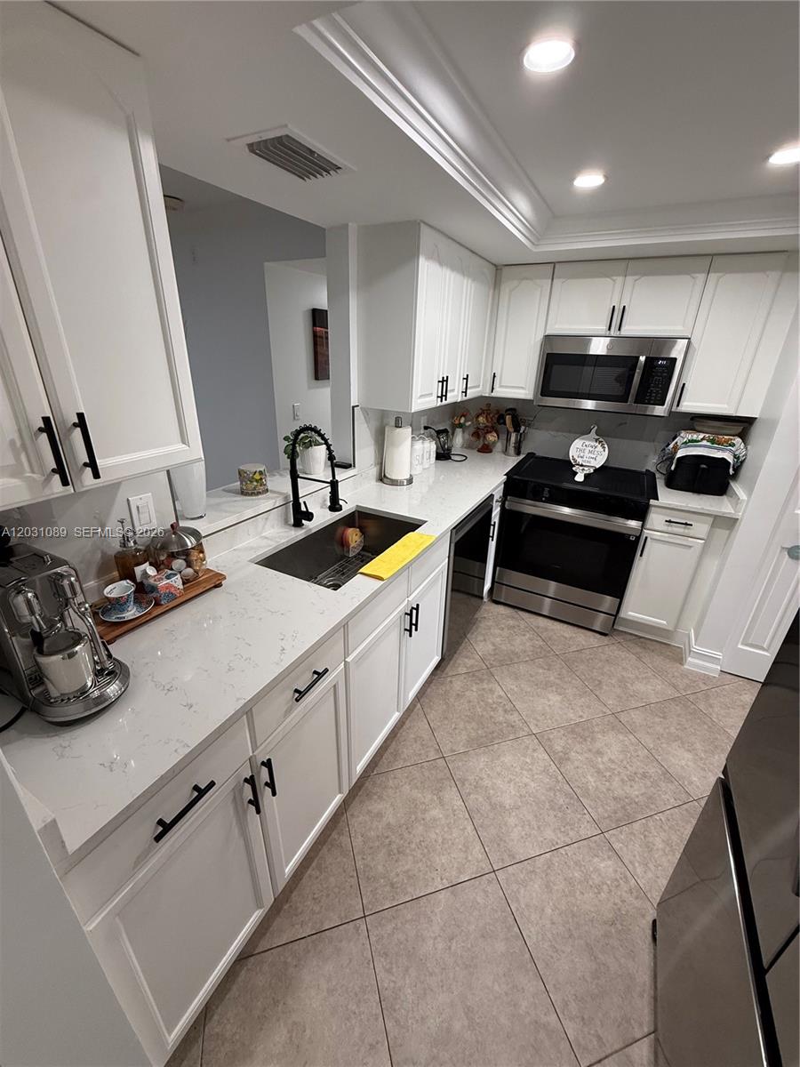 A white kitchen features stainless steel appliances, quartz countertops, and dark cabinet hardware — 1020 NW 80th Ave # 104, Margate FL 33063, MARGATE, FL