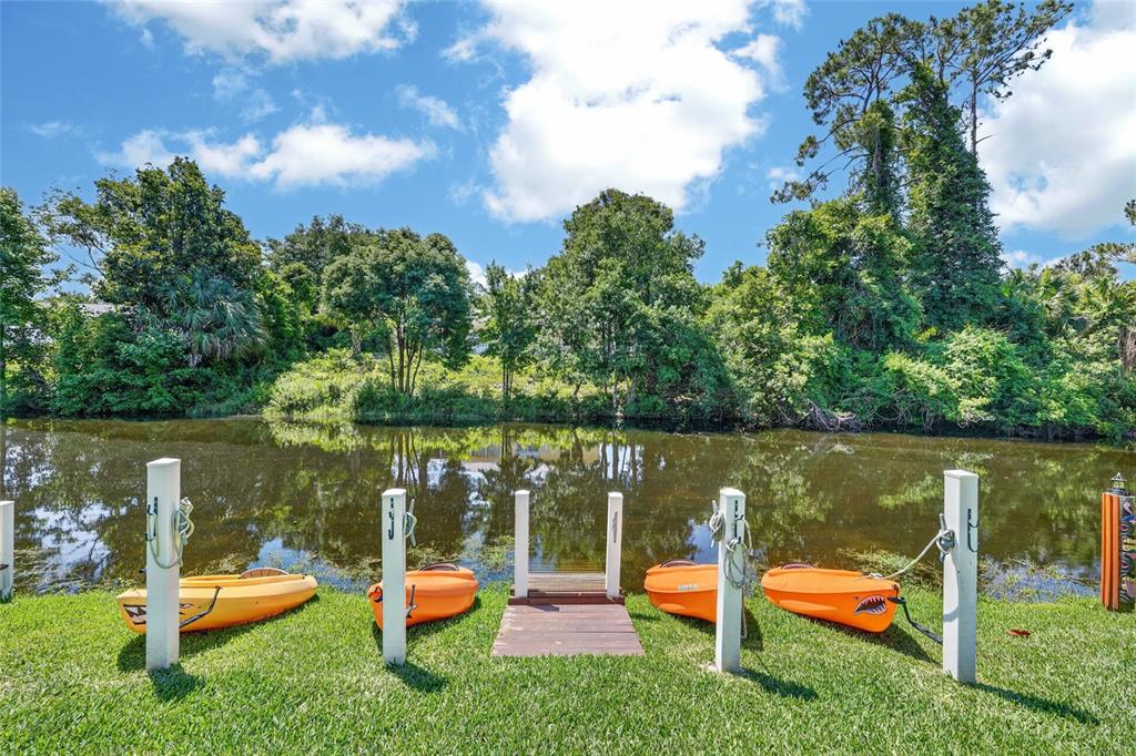 Four kayaks are docked on a grassy lawn beside a small wooden pier and canal — 36 FLAMINGO DRIVE, PALM COAST, FL