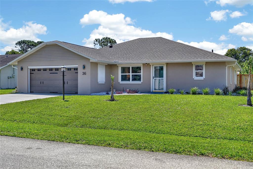 A single-story house with a beige exterior, a two-car garage, and a green lawn — 36 FLAMINGO DRIVE, PALM COAST, FL