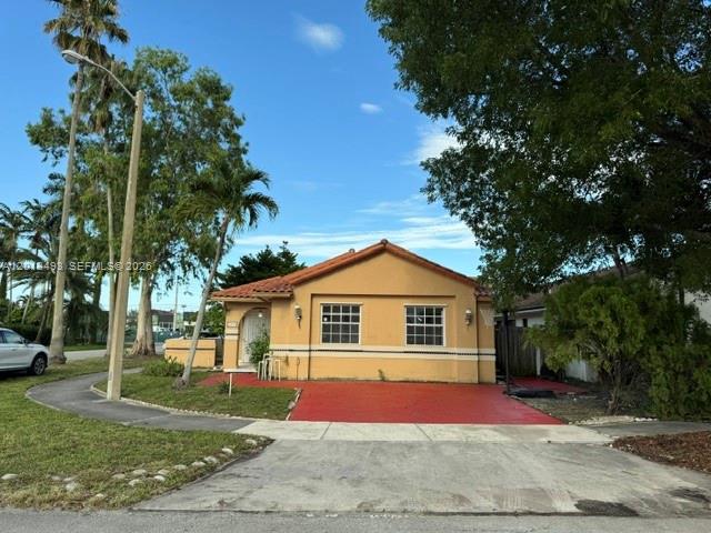 A single-story yellow house with a red driveway sits under a clear blue sky — 7599 W 4th Ct # 0, Hialeah FL 33014, HIALEAH, FL