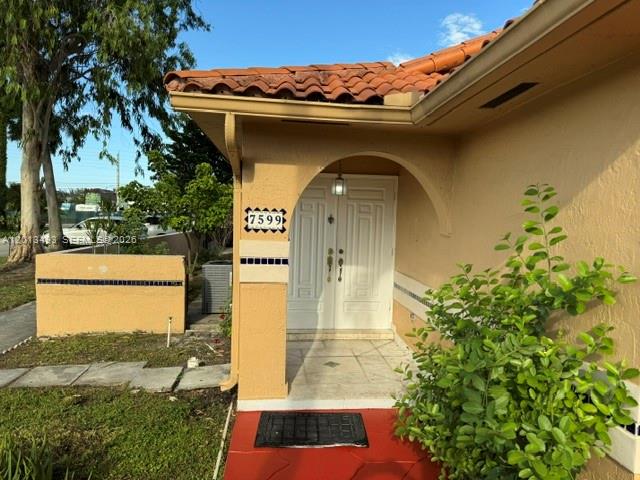 The exterior of a tan house features a tiled roof, double front doors, and landscaping — 7599 W 4th Ct # 0, Hialeah FL 33014, HIALEAH, FL