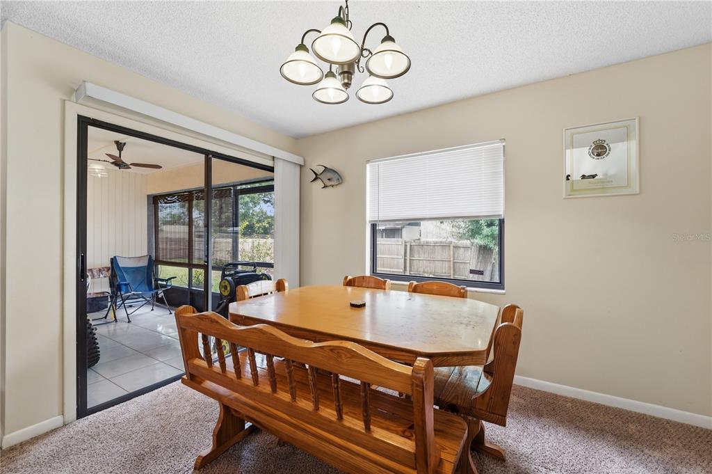 A dining room features a wooden table with bench seating, a chandelier, and a sliding door — 358 N FORK PLACE, LAKELAND, FL