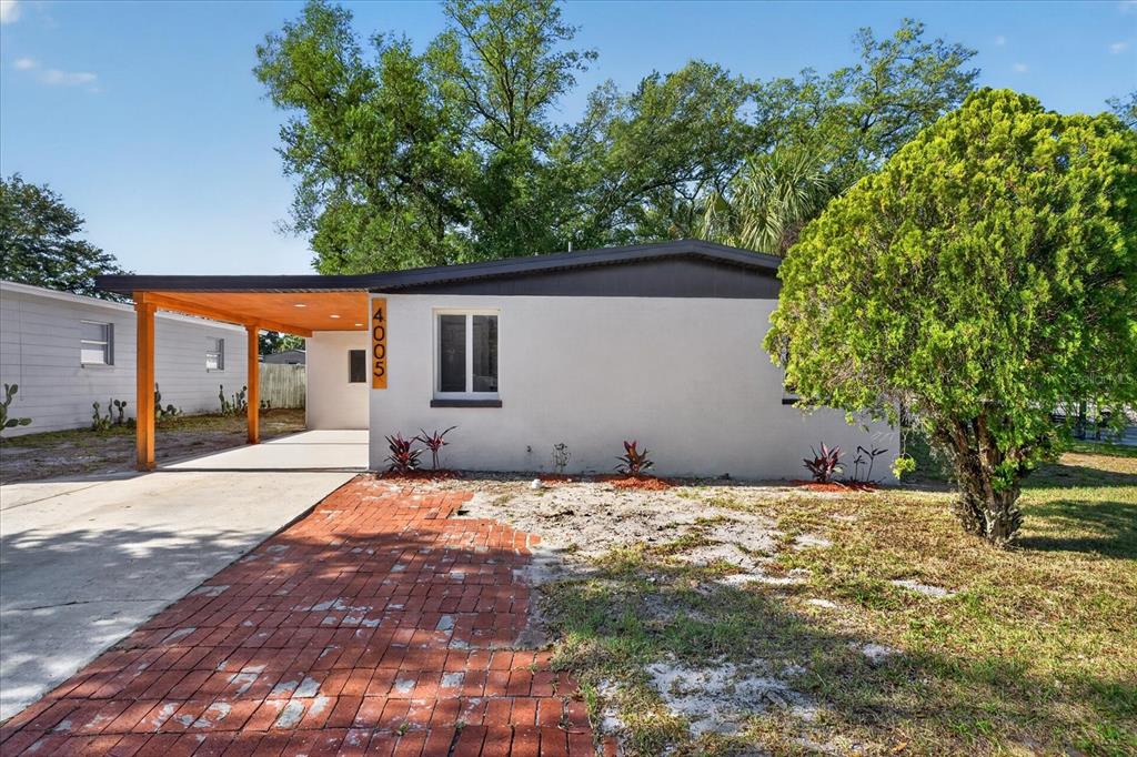 A single-story house with a carport, a brick walkway, and a large tree in front — 4005 E HENRY AVENUE, TAMPA, FL