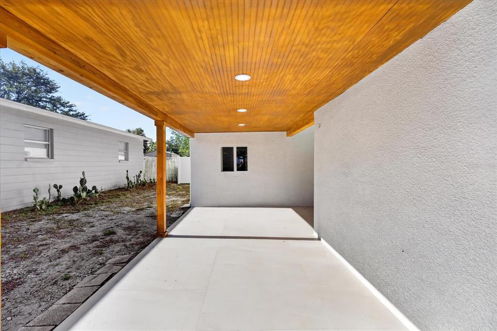 A covered patio with a wood-paneled ceiling, recessed lighting, and a white tiled floor — 4005 E HENRY AVENUE, TAMPA, FL