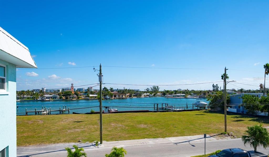 An elevated view shows a vacant grassy lot overlooking a canal with boat docks — 8200 BAYSHORE DRIVE UNIT 9, TREASURE ISLAND, FL
