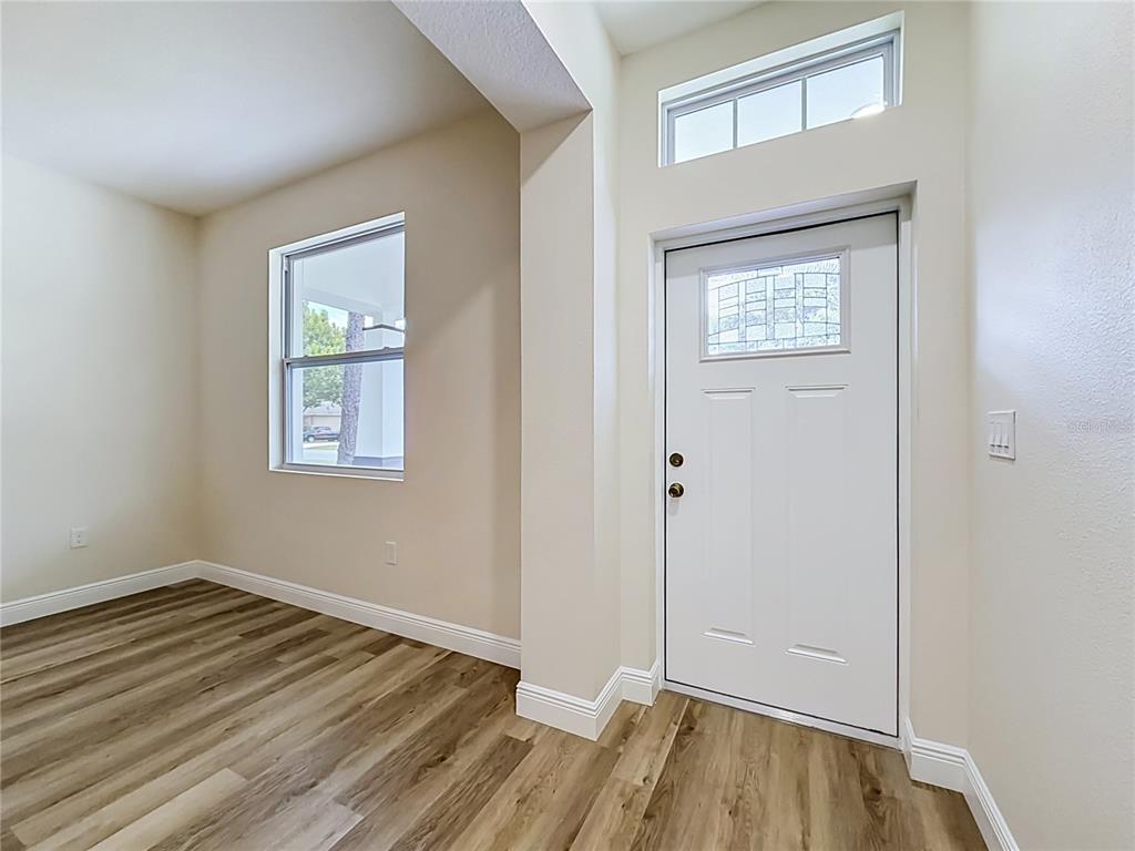 An entryway with wood-look flooring, a white front door, and a transom window above — 840 N TRIPLET LAKE DRIVE, CASSELBERRY, FL
