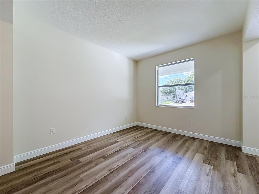 An empty room features light-colored walls, white trim, and wood-look vinyl plank flooring — 840 N TRIPLET LAKE DRIVE, CASSELBERRY, FL