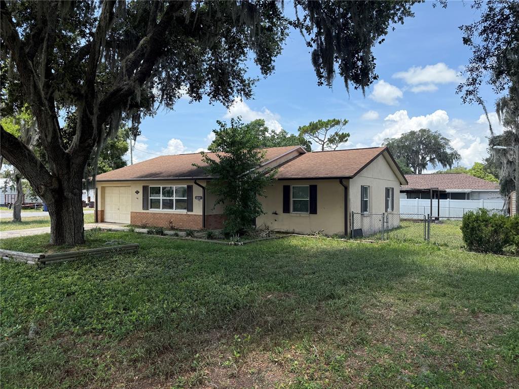 A single-story house with a tan exterior, a brown roof, and a front-facing garage — 1244 COUNTY ROAD 437, LAKE PANASOFFKEE, FL