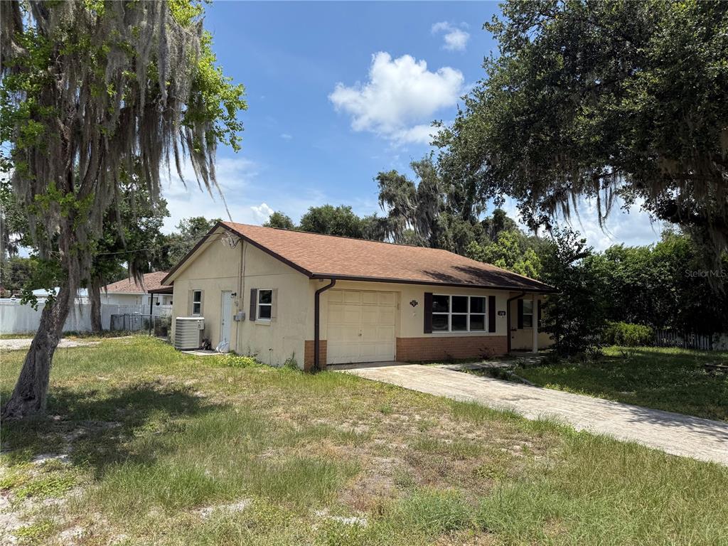 A single-story house with a garage, beige stucco siding, and a brown shingled roof — 1244 COUNTY ROAD 437, LAKE PANASOFFKEE, FL